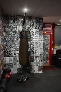 Sac de frappe devant un mur de coupures de presse de boxe, salle SBC Paris 16