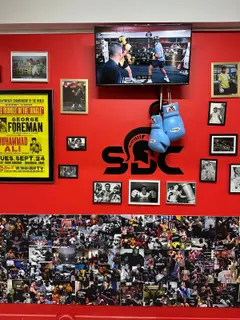 Mur rouge au logo SBC avec affiche George Foreman contre Muhammad Ali et gants de boxe, salle SBC Paris 15