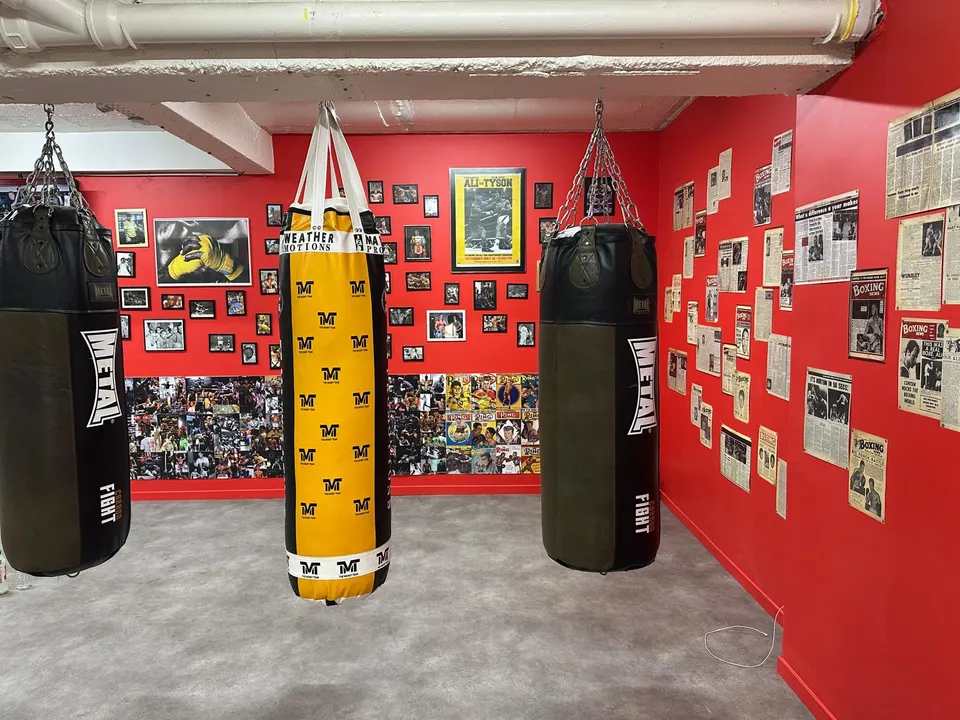Sacs de frappe devant les murs rouges couverts de photos de boxeurs, salle de boxe SBC Miollis (Paris 15e)