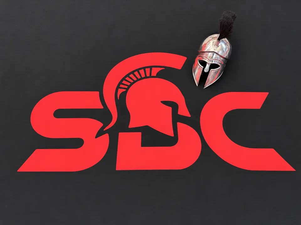 Logo Spartan Boxing Club imprimé sur le sol du ring, avec un casque spartiate en métal posé à côté